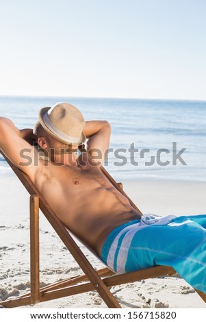 Handsome man on the beach sleeping with his hat covering his face