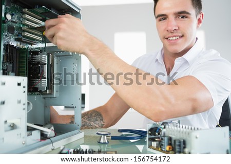 Handsome smiling computer engineer working at open computer in bright office