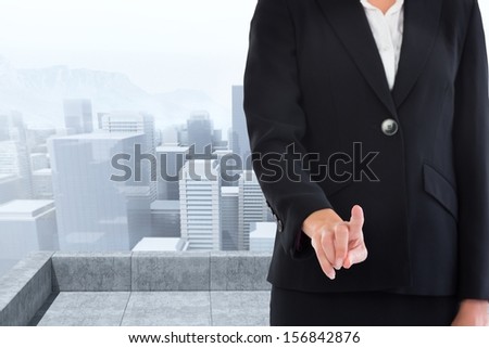 Composite image of businesswoman pointing at waist level standing on roof of building