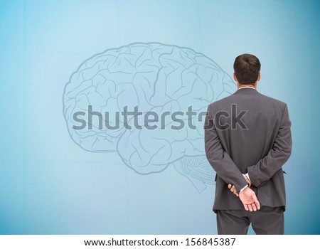 Composite image of businessman standing with hands behind back looking at fair brain on blue background