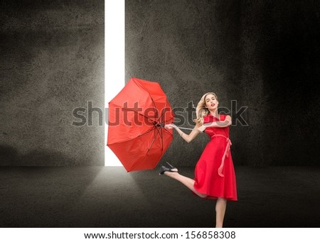 Composite image of beautiful woman wearing red dress holding umbrella standing in dark room