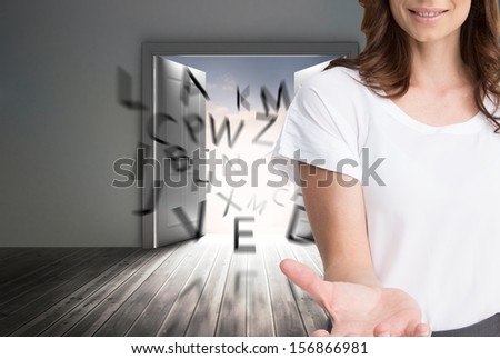 Composite image of attractive businesswoman showing her empty hand open in front of big door with floating letters