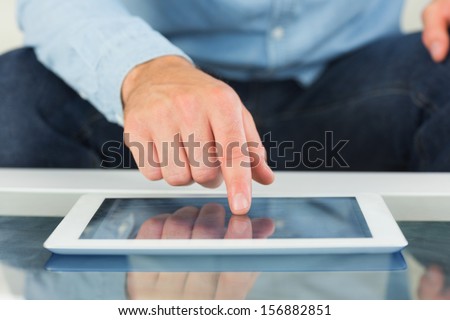 Close up of finger from man touching tablet in bright living room