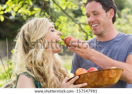 Young man feeding his girlfriend with an apple while laughing
