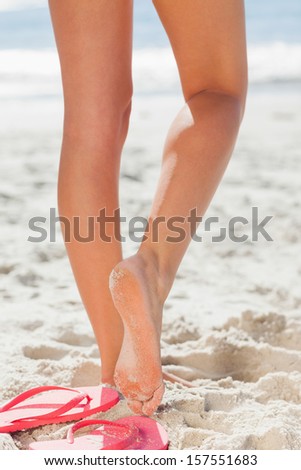 Woman\'s legs on beach against ocean with flip flops