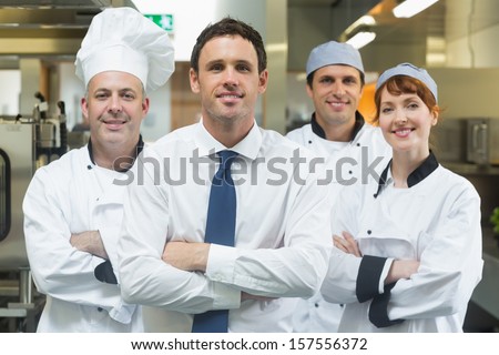 Restaurant manager standing in front of team of chefs smiling at camera