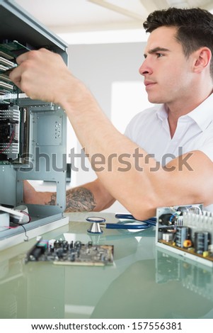 Handsome stern computer engineer working at open computer in bright office
