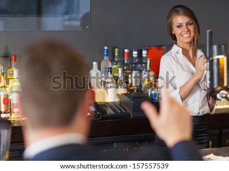 Handsome man ordering a drink from gorgeous waitress in a classy bar
