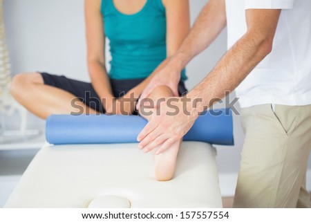 Physiotherapist checking patients leg in bright office