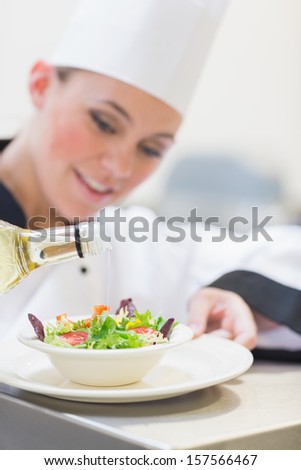 Chef Pouring Olive Oil Over Salad In Kitchen