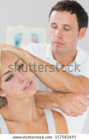 Calm physiotherapist massaging patients neck with elbow in bright office