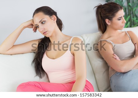 Two beautiful  women having a quarrel sitting on a couch in the living room