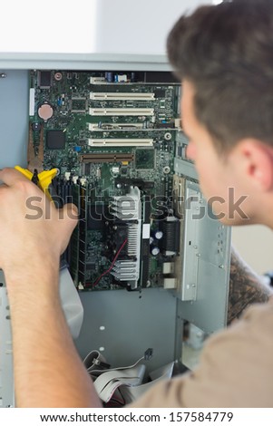 Computer engineer repairing open computer with pliers in bright office