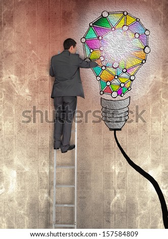 Rear view of businessman pointing at painted bulb on brown wall while standing on ladder