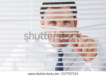 Handsome businessman spying through roller blind