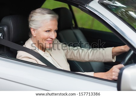 Smiling businesswoman driving classy car on a bright day