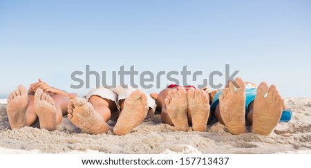 Feet of friends lying together on the beach