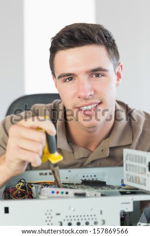 Handsome happy computer engineer repairing open computer in bright office