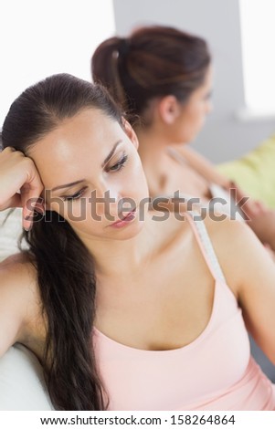 Annoyed woman sitting next to her friend on a couch in the living room