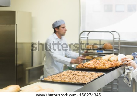Young male baker working in a kitchen wearing a work coat