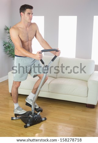 Serious handsome man training on stair climber in bright living room