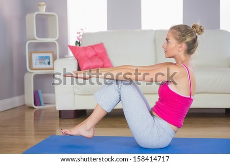 Sporty focused blonde doing core exercise in bright living room