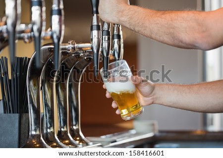 Barman\'S Arms Pulling A Pint Of Beer Behind The Bar