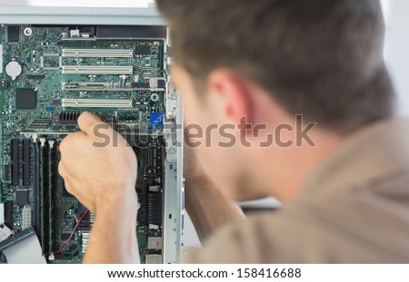 Computer engineer examining computer in bright office