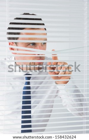 Good looking businessman spying through roller blind