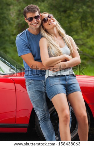 Loving couple hugging and leaning against cabriolet on a sunny day
