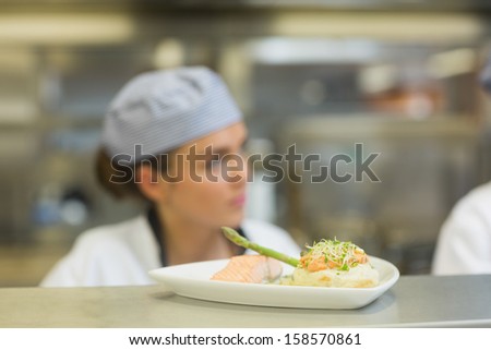 Salmon dinner on a plate on order station with chef in background