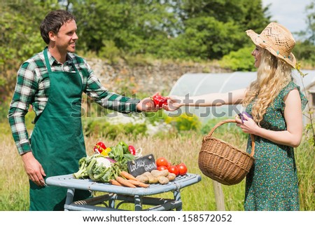 Beautiful woman buying vegetables at farmers stall from a young farmer