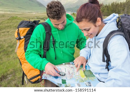 Couple sitting after hiking uphill and consulting map in the countryside