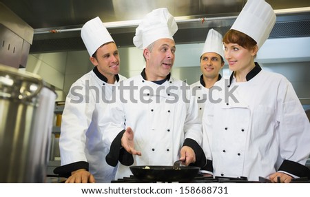 Experienced head chef explaining food to his colleagues in the kitchen