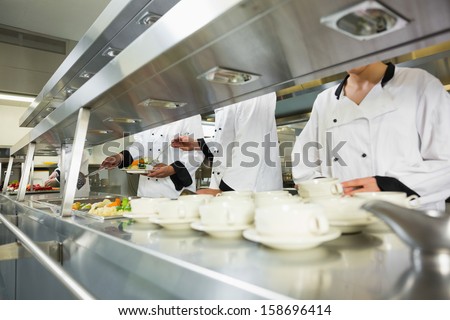 Four chefs working in a kitchen at the order station