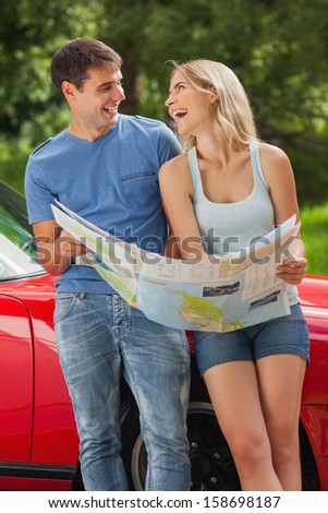 Smiling young couple on a sunny day reading map