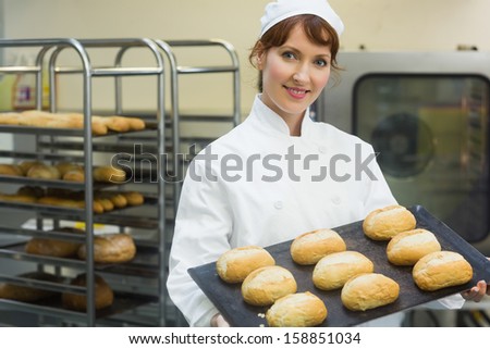 Happy Female Baker Showing Some Rolls On A Baking Tray Smiling At The Camera