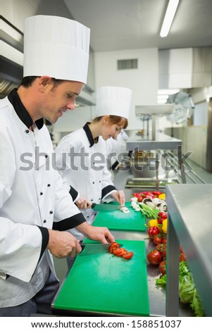 Two young chefs cutting vegetables in industrial kitchen