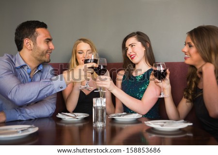 Friends clinking red wine glasses at a bar and chatting