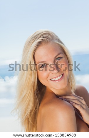 Blonde woman at the beach against the sea on holidays smiling at camera