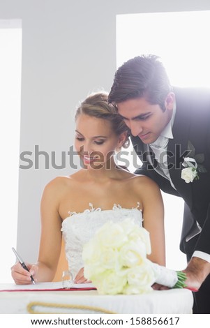 Attractive young couple signing wedding contract sitting at desk