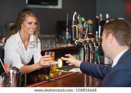 Beautiful waitress serving handsome businessman in a classy bar
