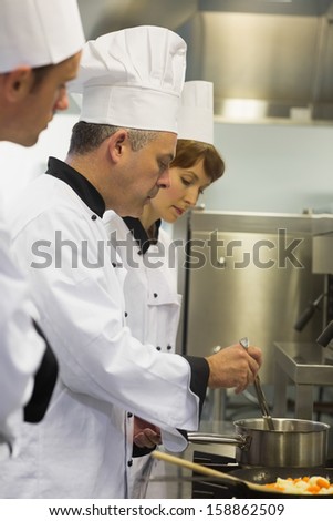 Head chef inspecting his students pot in a kitchen