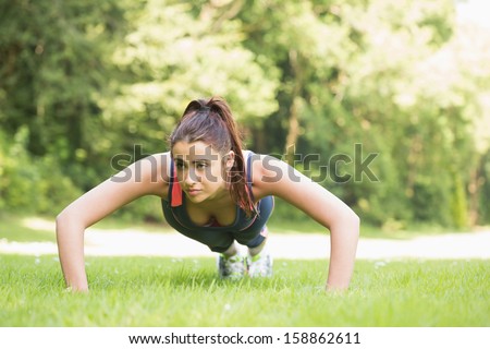 Serious fit woman doing plank position outside on the grass