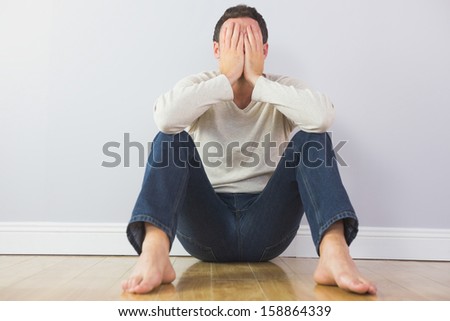 Casual upset man covering his face with hands in bright room