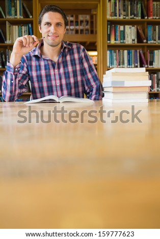 Portrait of a smiling mature male student studying at desk in the library