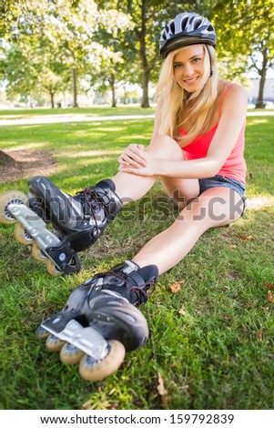 Casual gorgeous blonde wearing roller blades and helmet in a park