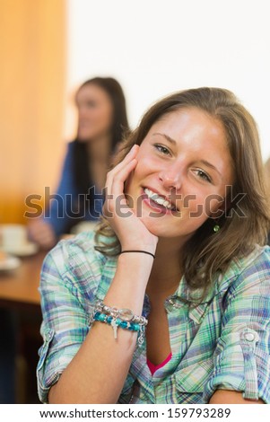 Close-up portrait of a smiling female with students in background at  the coffee shop
