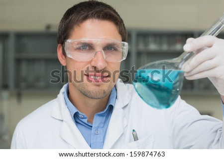 Close-up portrait of a male researcher  holding flask with blue liquid in the lab