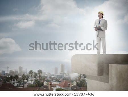 Full length of a male architect with hard hat and clipboard against the sky and cityscape